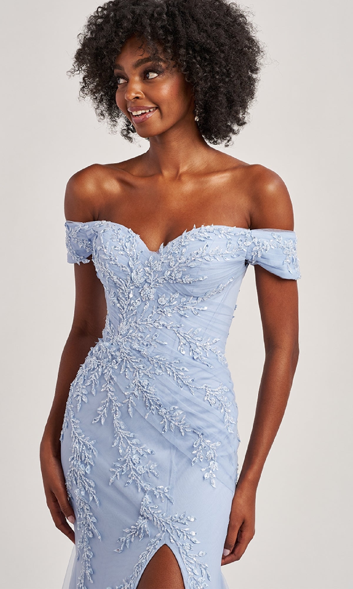 A woman models the Off-the-Shoulder Long Prom Dress: Colette CL8645 in light blue, featuring floral embroidery, a mermaid silhouette, and a front slit—a stunning choice for any formal occasion.